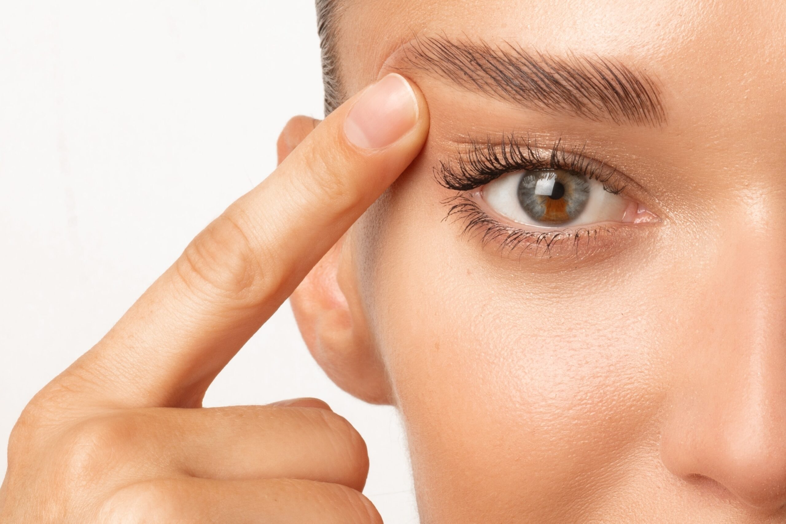 Upper vs Lower Eyelid Surgery Woman has pointer finger on eyebrow